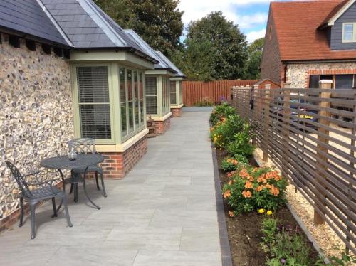 a patio with a table and chairs and a fence at Blundens Holiday Lets - Tower in Boxgrove