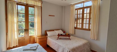 a bedroom with two beds and two windows at Casa de Campo Chinkay - Lunahuana in Lunahuaná