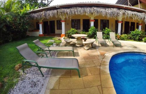 um pátio com uma mesa e cadeiras ao lado de uma piscina em Hotel Esperanza em Carrillo