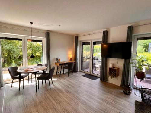 エムデンにあるNeues Apartment Nordisch bei Nature by Fewo & Zimmer Brunsのテーブルと椅子とテレビのあるリビングルーム