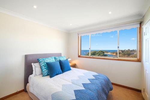 ein Schlafzimmer mit einem Bett und einem großen Fenster in der Unterkunft Scenic Beachside Apartment, near Bar & Restaurant in Terrigal