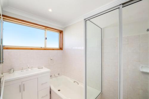 ein Badezimmer mit einer Dusche, einem Waschbecken und einer Badewanne in der Unterkunft Scenic Beachside Apartment, near Bar & Restaurant in Terrigal