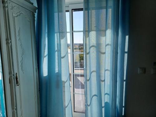 a window with blue curtains in a room at Sunny Room - Sofia's Happy House - Almodôvar Ourique Room 2 in Aldeia dos Fernandes