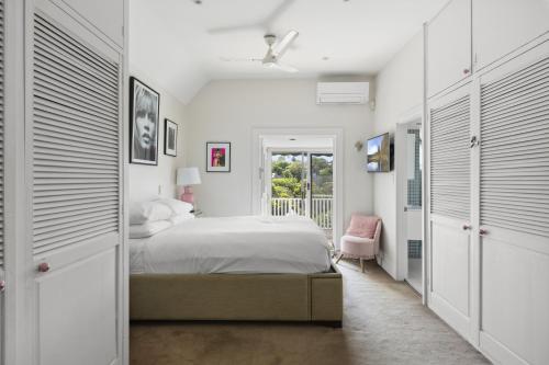 a white bedroom with a bed and a balcony at Poolside Stay - Close to Taronga Zoo & Luna Park in Sydney