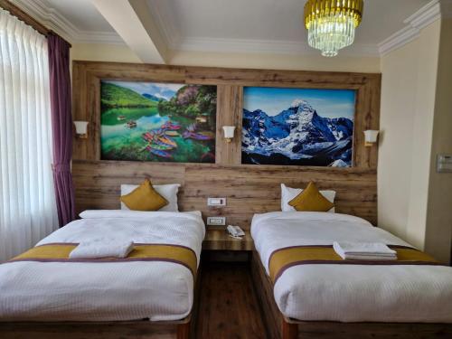 twee bedden in een kamer met een schilderij aan de muur bij Prem Durbar Hotel in Changunarayan