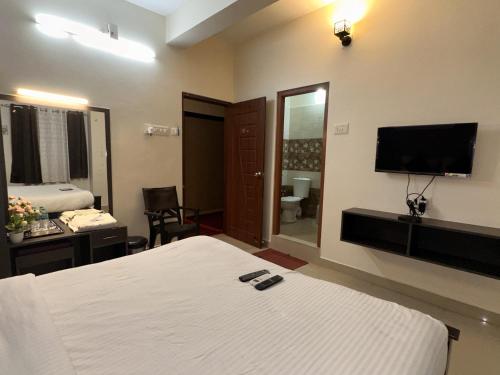 een hotelkamer met een bed en een flatscreen-tv bij Srichand Business Class Rooms in Tiruvallūr