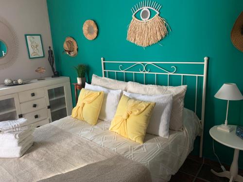 Dormitorio azul con cama con almohadas amarillas en Apartamentos la Jayma del Arte en Asque
