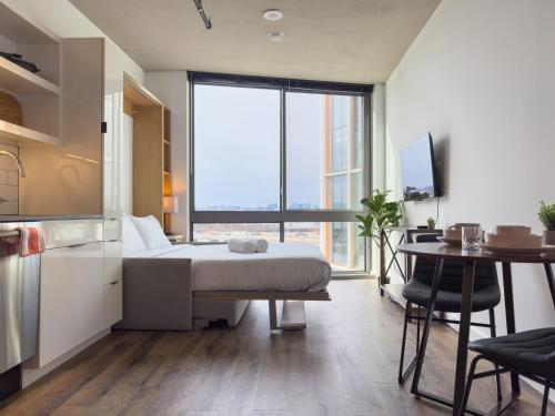 a bedroom with a bed and a table and a kitchen at River View Suite - The Wharf DC by Monthier in Washington, D.C.