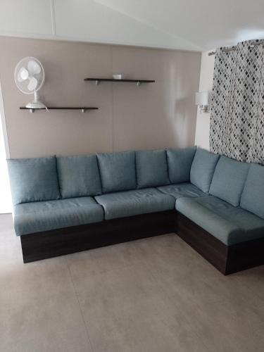 a blue couch sitting in a living room at MHVACANCES LOUENT PLUSIEURS MOBILHOMES DANS CAMPING 4 ETOILES PROCHE CHATEAUX et ZOO BEAUVAL in Onzain