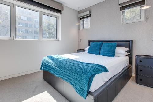 a bedroom with a large bed with blue pillows at Explore Sydney from Stylish North Shore Apartment in Sydney