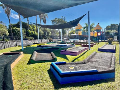 a playground with several trampolines on the grass at Diamond Beach Holiday Park in Diamond Beach