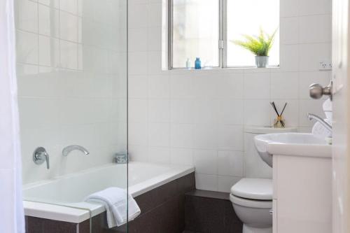a bathroom with a tub and a toilet and a sink at Sunny Apartment in Quiet and Green Neighbourhood in Sydney