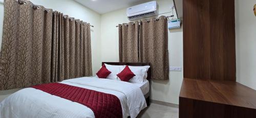 a bedroom with a bed with red pillows and curtains at Hotel NJ RESIDENCY NEAR DLF IT PARK, RMZ SOFTWARE PARK, L&T ECC, CHENNAI TRADE CENTRE & MIOT in Chennai