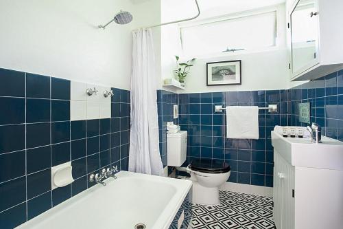 a blue tiled bathroom with a toilet and a sink at Treetop Retreat Five Minute Stroll To The Beach in Sydney