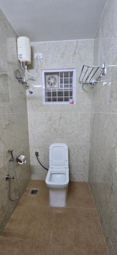 a bathroom with a white toilet and a window at Hotel NJ RESIDENCY NEAR DLF IT PARK, RMZ SOFTWARE PARK, L&T ECC, CHENNAI TRADE CENTRE & MIOT in Chennai
