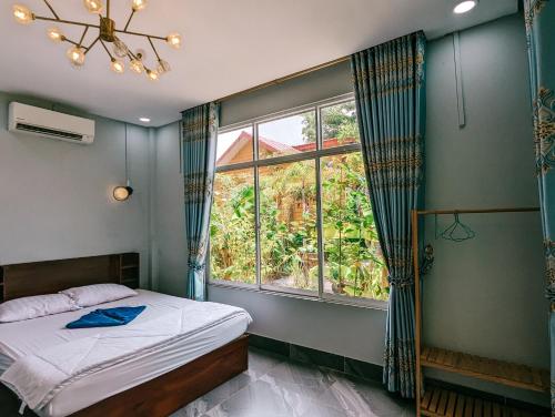 sypialnia z łóżkiem i dużym oknem w obiekcie Yellow Star Hostel w mieście Kâmpôt