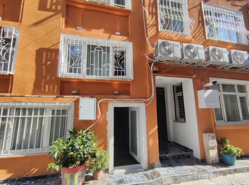 un bâtiment orange avec des fenêtres et des plantes devant lui dans l'établissement IMMOR AKKUS HOTEL, à Istanbul