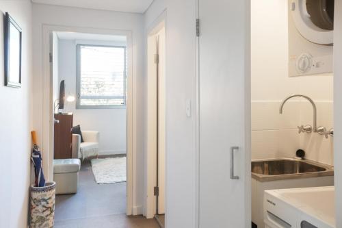 een keuken met witte muren, een wastafel en een deur bij Spacious Modern Apartment In Sydney's North Shore in Sydney