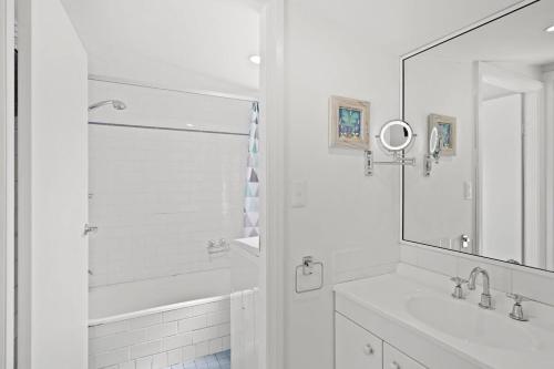 een witte badkamer met een wastafel en een spiegel bij Immaculate Beachside Home with Fireplace and Patio in Bateau Bay