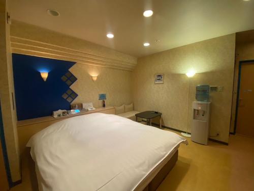 HOTEL Fairy tale 養父店 في Yōka: غرفة نوم بسرير ابيض كبير بجدار ازرق
