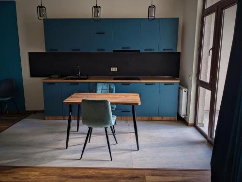 a kitchen with blue cabinets and a wooden table and a chair at Milky Way in Stepantsminda