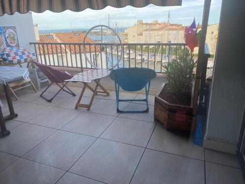 - un balcon avec 2 chaises, une table et une balançoire dans l'établissement Bel appartement les roches Brunes vue mer, au Cap d'Agde