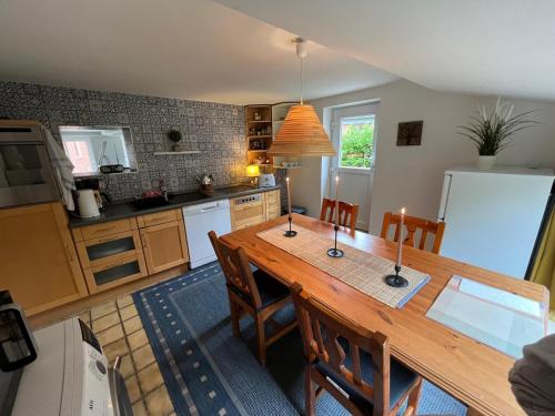 a kitchen with a wooden table with chairs and a refrigerator at Ferienhus Aline in Krummhörn