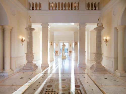 a hallway with columns and a person in the distance at Mandola Rosa Grecotel Boutique Resort in Loutra Killinis