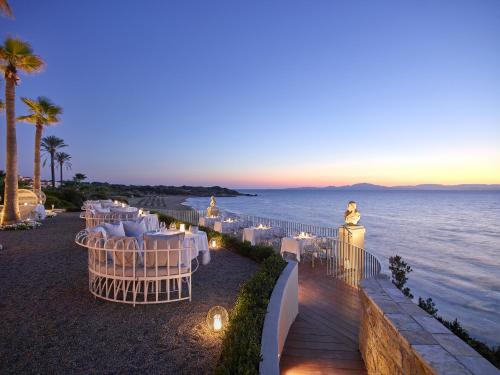 a restaurant with white tables and chairs on the beach at Mandola Rosa at Riviera Olympia, A Grecotel Resort to Live in Loutra Killinis