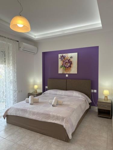 a bedroom with a large bed with a purple wall at Iliana Apartment in Afantou