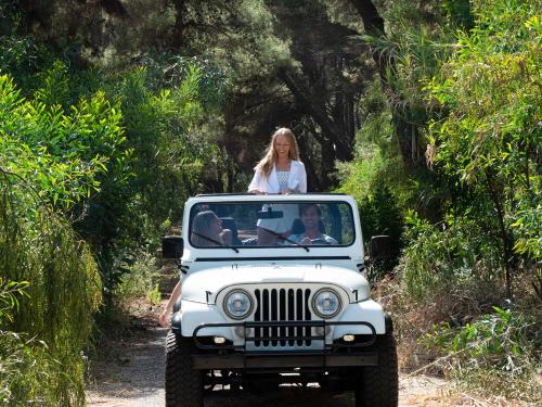a woman riding in the back of a jeep on a dirt road at Mandola Rosa at Riviera Olympia, A Grecotel Resort to Live in Loutra Killinis