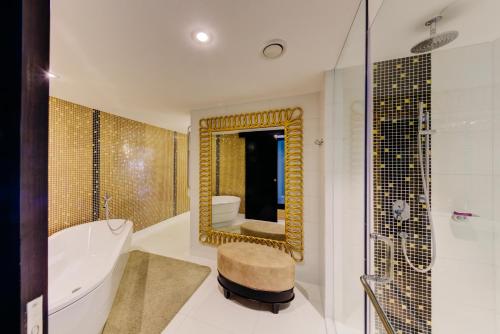 a bathroom with a tub and a toilet and a mirror at Cinnamon Grand Colombo in Colombo