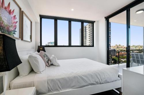 Schlafzimmer mit einem weißen Bett und großen Fenstern in der Unterkunft Convenient 2-Bed Apartment with Panoramic Views in Brisbane