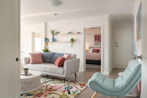 Cosy 2-Bed Apartment in the Heart of Strathfield في سيدني: غرفة معيشة مع أريكة وكرسي