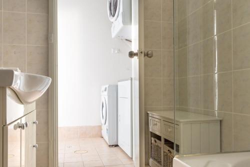 a bathroom with a sink and a washing machine at Cosy 2-Bed Apartment in the Heart of Strathfield in Sydney