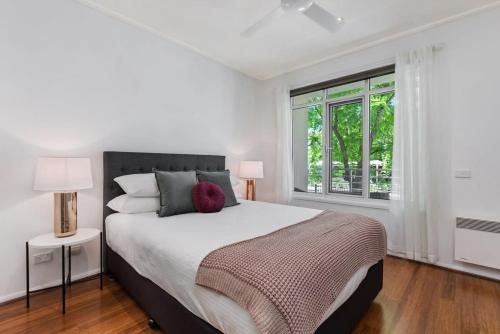 een witte slaapkamer met een groot bed en een raam bij Classy Beachside Unit with Parking and Gym in Melbourne