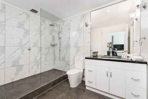 een badkamer met een douche, een toilet en een wastafel bij Classy Beachside Unit with Parking and Gym in Melbourne
