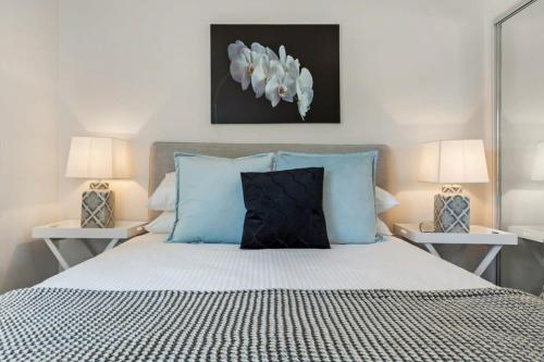een slaapkamer met een bed met blauwe kussens en 2 lampen bij Chic 2-Bed Oasis in South Melbourne's Heart in Melbourne