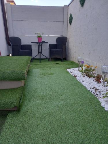 a patio with green grass and a table and chairs at Apartament în regim in Pantelimon
