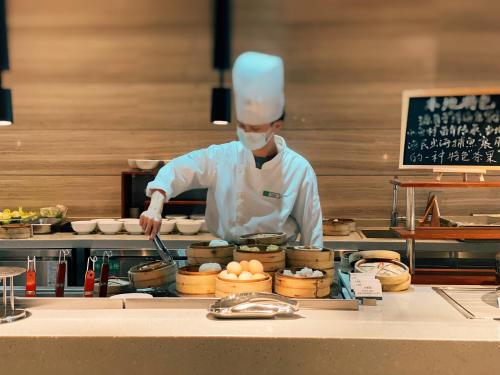 a chef is preparing food in a kitchen at Holiday Inn Zhuhai City Center by IHG in Zhuhai