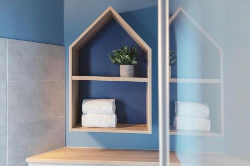 uma casa de banho com uma prateleira com toalhas e uma parede azul em Yggotel Mejse em Viena