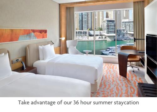 een hotelkamer met 2 bedden en een televisie bij Crowne Plaza Dubai Marina, an IHG Hotel in Dubai