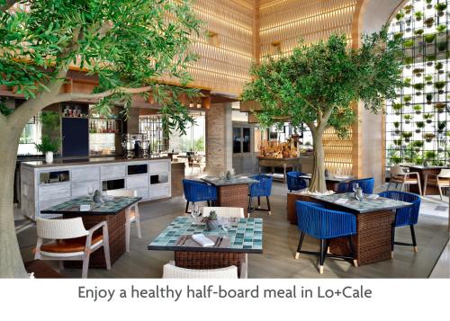 um restaurante vazio com mesas, cadeiras e árvores em Crowne Plaza Dubai Marina, an IHG Hotel em Dubai