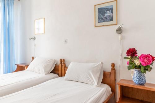 two beds in a room with a vase of roses at Sifnos studio 4 in Sifnos