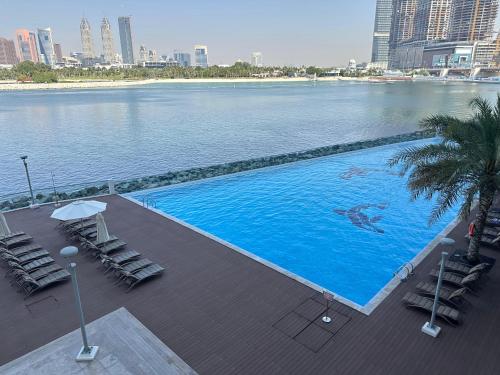 a large swimming pool next to a large body of water at 2BDR apartment with full sea view and Dubai Marina view Azure Residences in Dubai