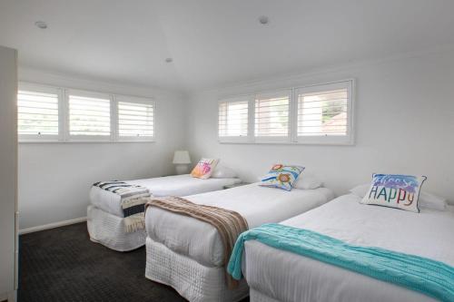 two beds in a room with windows at Elegant 3-Bed Heritage House with Swimming Pool in Sydney