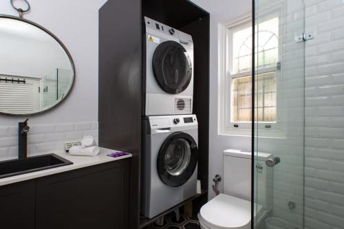 a bathroom with a washing machine and a sink at Elegant 3-Bed Heritage House with Swimming Pool in Sydney
