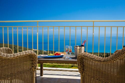 a table and chairs on a balcony with a view of the ocean at Villa Lemoni Skala - Heated Infinity Pool with Sea Views & Outside Cinema in Old Skala