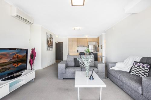 a living room with a couch and a tv at Lakeside Family Oasis with Pool, Gym and Balcony in Gold Coast