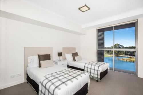 two beds in a room with a window at Lakeside Family Oasis with Pool, Gym and Balcony in Gold Coast